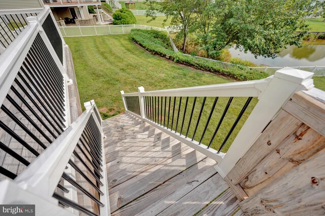 wooden deck featuring a yard, a water view, and fence