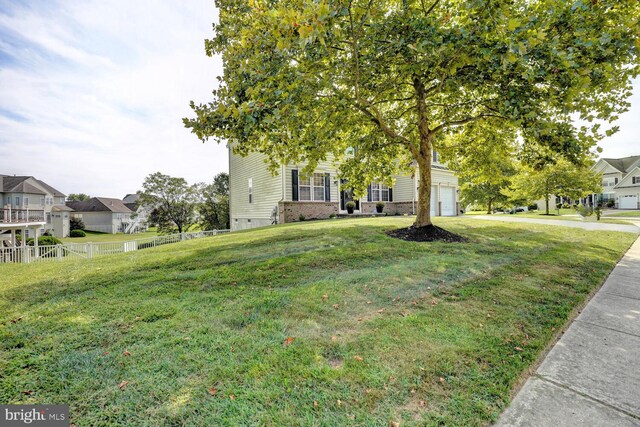 obstructed view of property with brick siding, a front yard, fence, a garage, and driveway