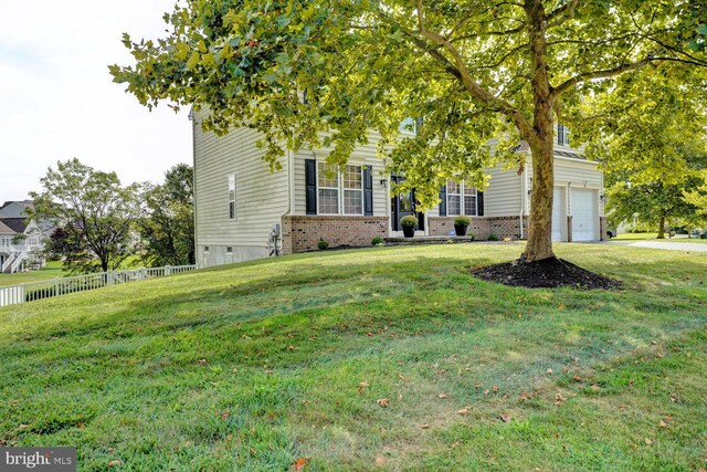 obstructed view of property with a garage, driveway, brick siding, fence, and a front yard