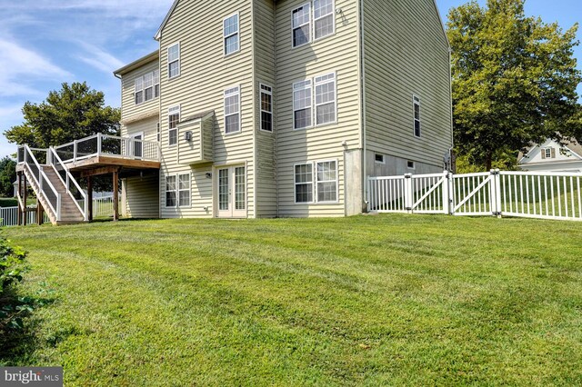 rear view of house featuring a lawn, stairway, a gate, fence, and a deck