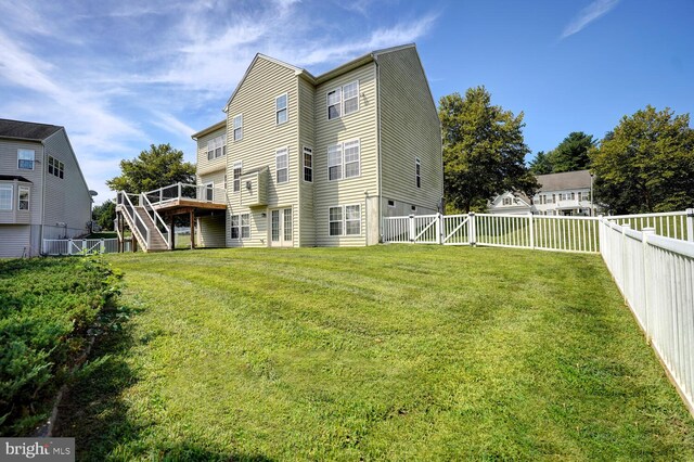 back of property featuring a fenced backyard, stairway, a deck, and a lawn