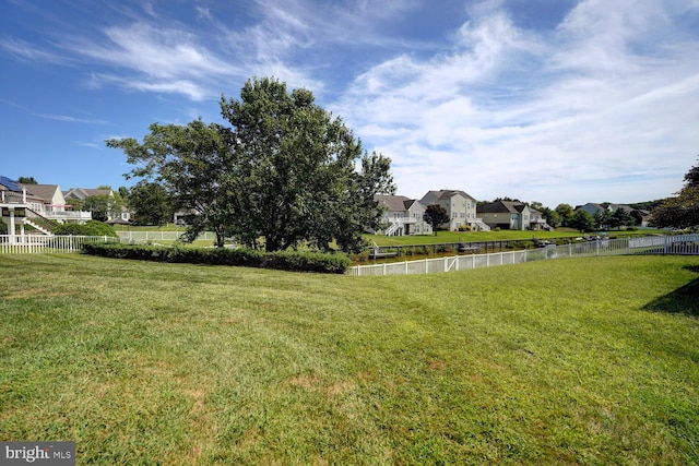 view of yard featuring a water view, fence, and a residential view