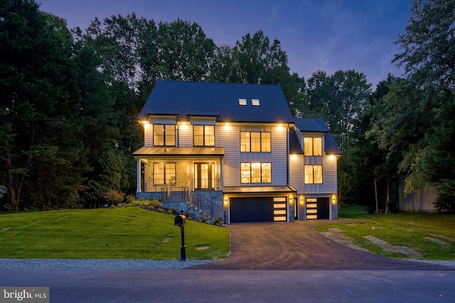 contemporary house featuring an attached garage, driveway, a porch, and a front yard