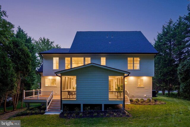 back house at dusk featuring a yard and a deck