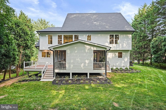 back of property with a shingled roof, a sunroom, a yard, and a deck