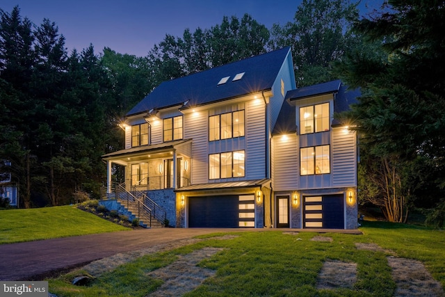 contemporary home featuring driveway, a standing seam roof, an attached garage, and a front yard