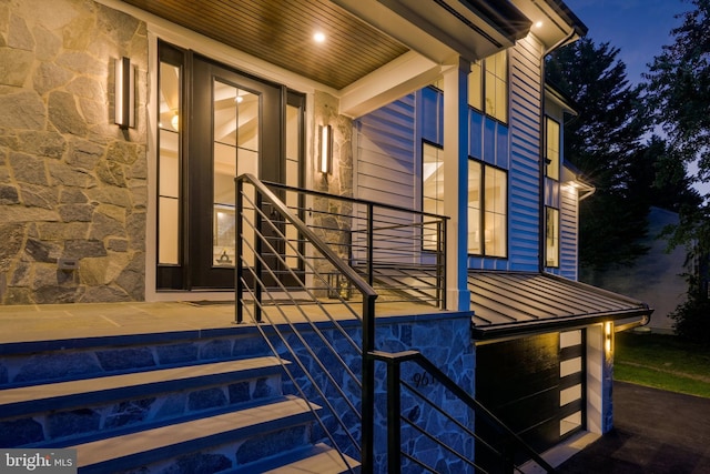 property entrance featuring stone siding, metal roof, and a standing seam roof