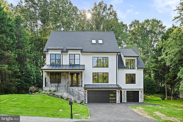 view of front of home with a garage, a standing seam roof, stone siding, and a front lawn