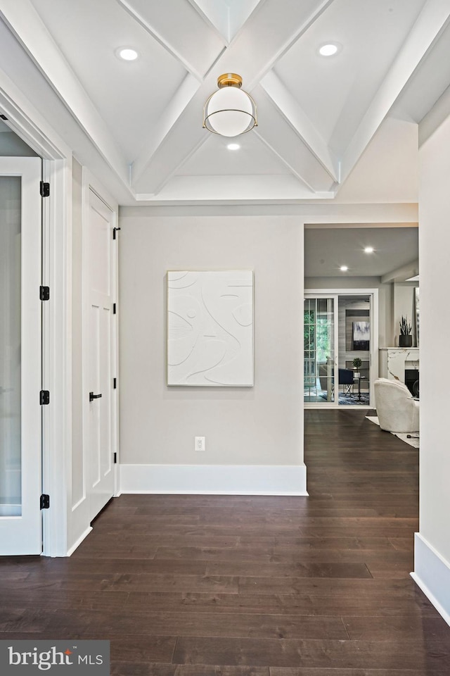 interior space with baseboards, wood finished floors, and beamed ceiling