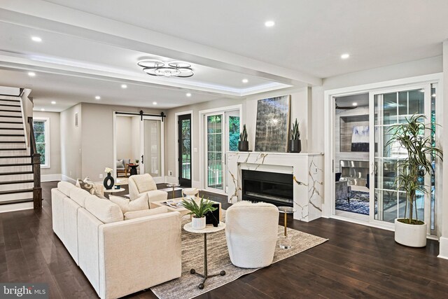 living room with a high end fireplace, dark hardwood / wood-style flooring, and a barn door