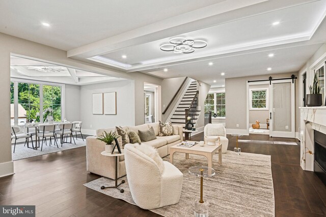 living room featuring a barn door, a high end fireplace, dark hardwood / wood-style flooring, and a notable chandelier