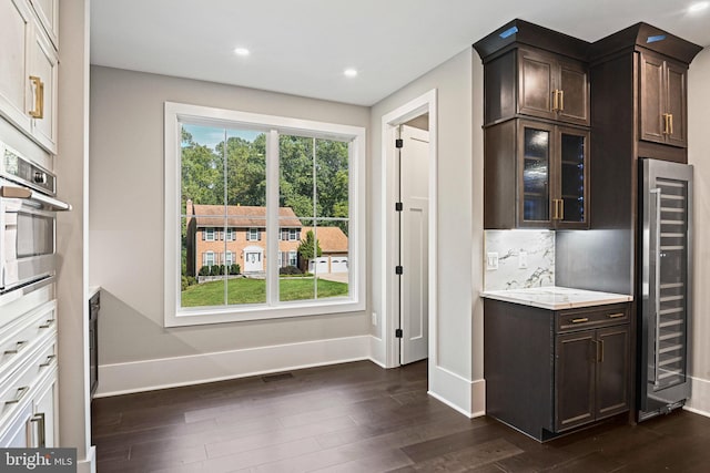 kitchen with dark brown cabinets, wine cooler, stainless steel oven, and decorative backsplash