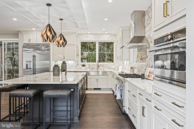 kitchen with high quality appliances, light stone counters, a kitchen island, wall chimney exhaust hood, and a breakfast bar area