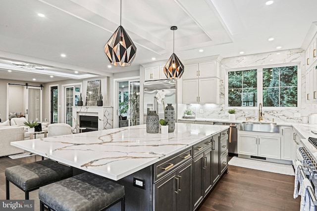 kitchen with a barn door, a sink, white cabinets, open floor plan, and high end appliances