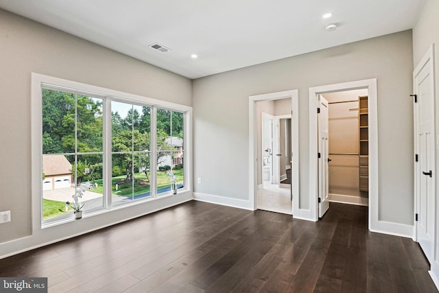 unfurnished room with dark wood-type flooring, visible vents, and baseboards