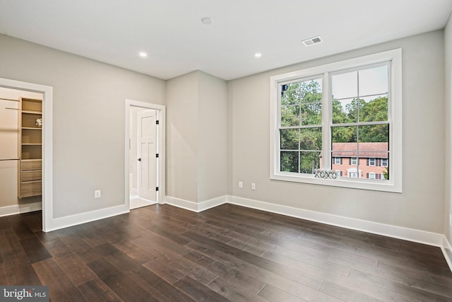 spare room with dark wood-style floors, recessed lighting, visible vents, and baseboards