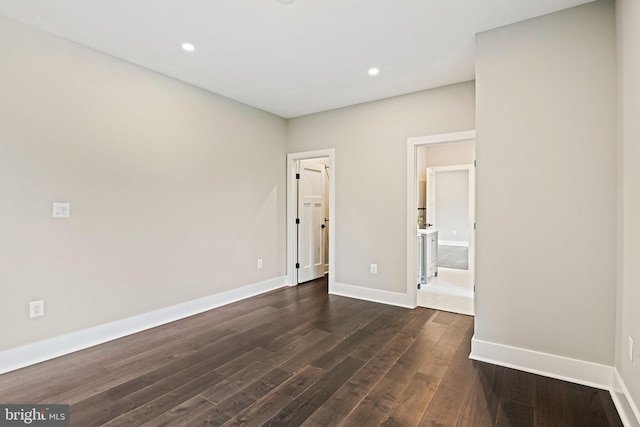 spare room with dark wood-type flooring, recessed lighting, and baseboards