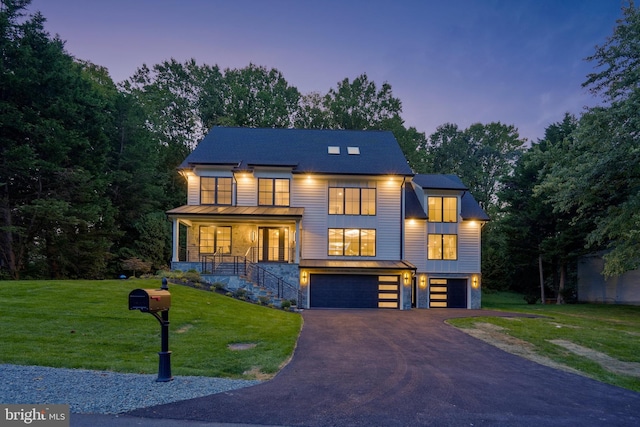 view of front facade featuring metal roof, aphalt driveway, a garage, a front lawn, and a standing seam roof