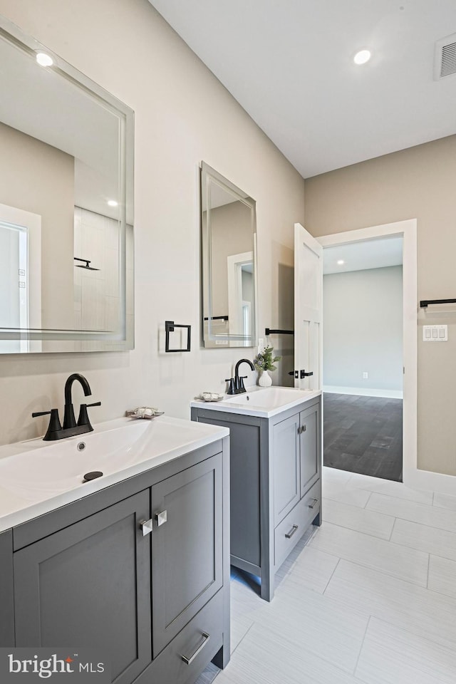 bathroom featuring visible vents, two vanities, a sink, and recessed lighting