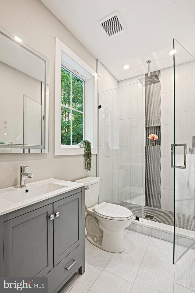 bathroom featuring vanity, toilet, an enclosed shower, and tile patterned flooring