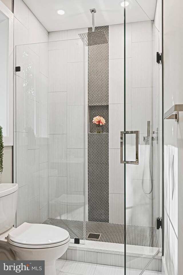 bathroom featuring tile walls, toilet, an enclosed shower, and tile patterned flooring