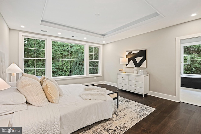 bedroom with wood-type flooring, a tray ceiling, baseboards, and recessed lighting