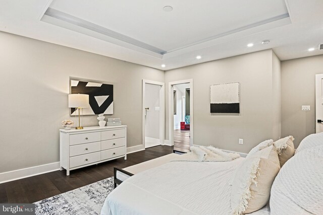 bedroom with a raised ceiling and dark hardwood / wood-style flooring