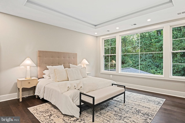 bedroom featuring a tray ceiling, dark wood-type flooring, visible vents, and baseboards