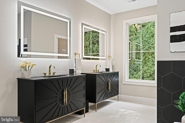 bathroom featuring tile patterned flooring, two vanities, a sink, and visible vents