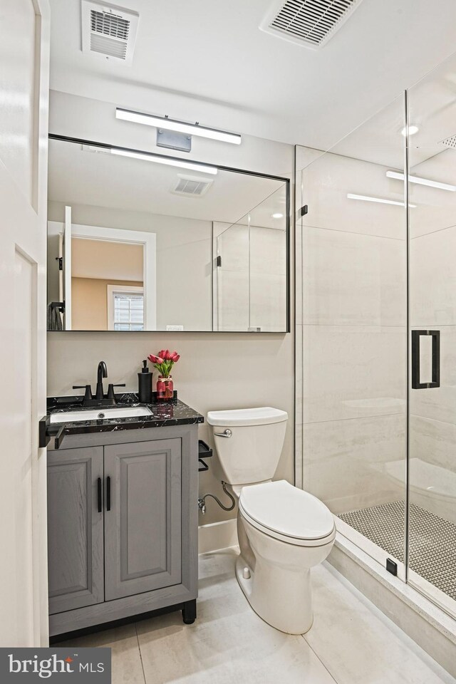 bathroom featuring tile patterned flooring, vanity, toilet, and an enclosed shower