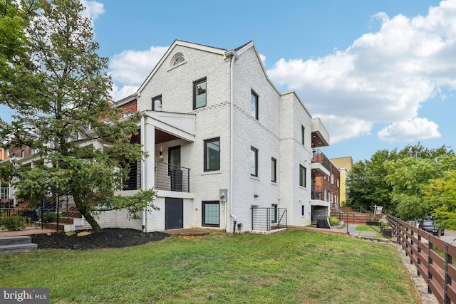 view of home's exterior with a balcony and a yard