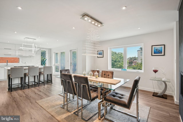 dining area featuring baseboards, recessed lighting, a chandelier, and light wood-style floors