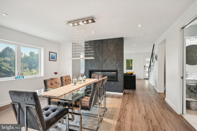 dining room featuring a chandelier, a fireplace, baseboards, and wood finished floors