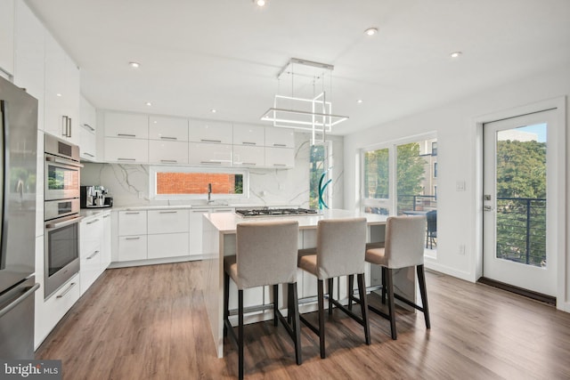 kitchen with wood finished floors, modern cabinets, a kitchen island, and white cabinets