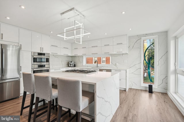 kitchen featuring wood finished floors, a kitchen island, white cabinetry, appliances with stainless steel finishes, and modern cabinets