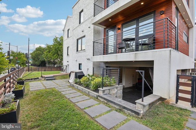 back of property featuring a lawn, a patio, and a balcony