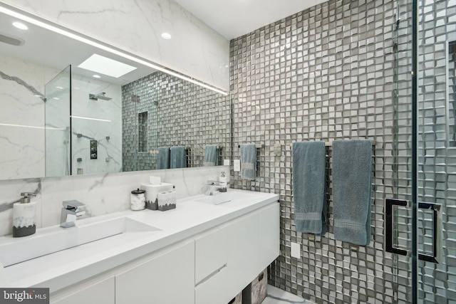 bathroom with tile walls, walk in shower, a skylight, and vanity