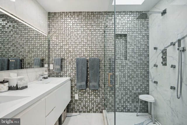 full bathroom featuring marble finish floor, tile walls, double vanity, a sink, and a shower stall