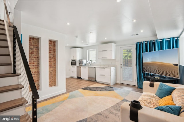 living room featuring recessed lighting, visible vents, baseboards, stairs, and light wood finished floors