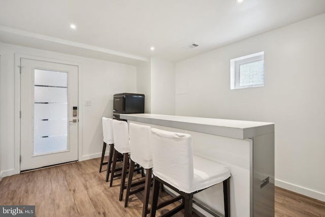 bar featuring light wood-type flooring, visible vents, and baseboards