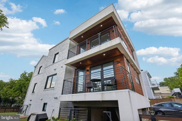 exterior space featuring a balcony and brick siding