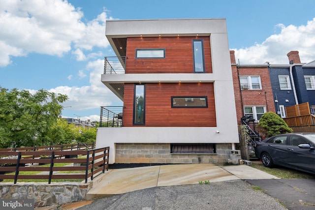 view of front of home featuring fence, a balcony, and stucco siding