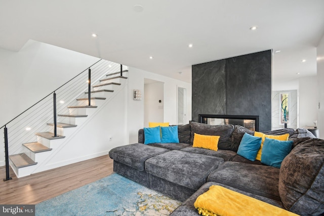 living room with recessed lighting, wood finished floors, a multi sided fireplace, baseboards, and stairway