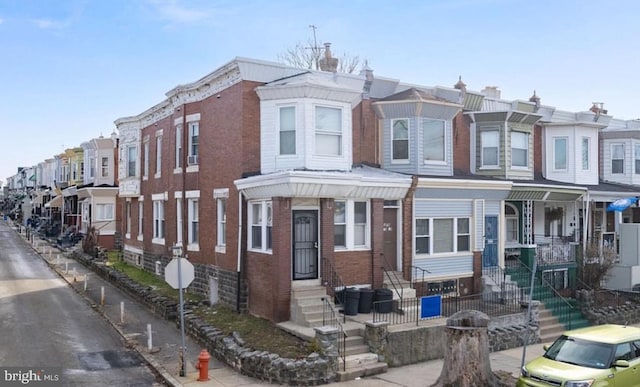 townhome / multi-family property featuring brick siding, a residential view, and entry steps