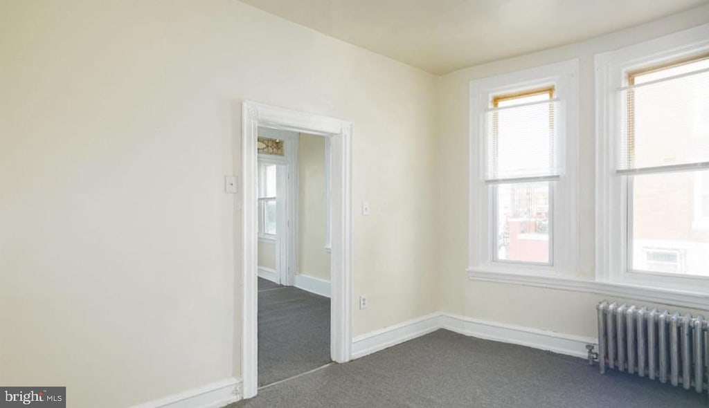 carpeted spare room featuring radiator heating unit