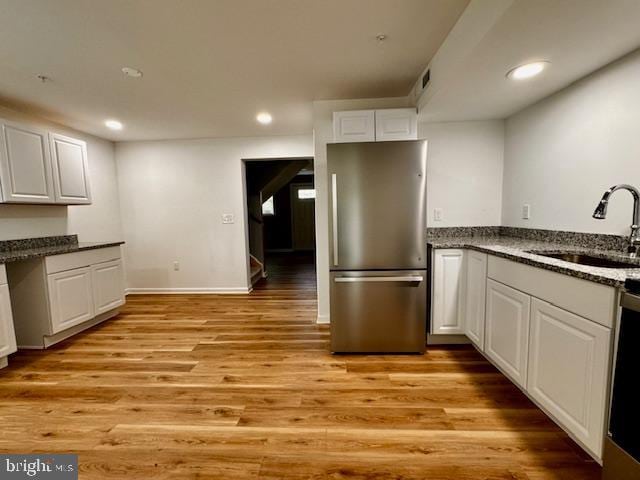 kitchen featuring appliances with stainless steel finishes, light hardwood / wood-style floors, white cabinetry, and sink