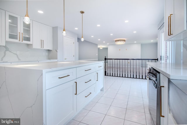 kitchen featuring glass insert cabinets, light stone countertops, dishwasher, pendant lighting, and decorative backsplash