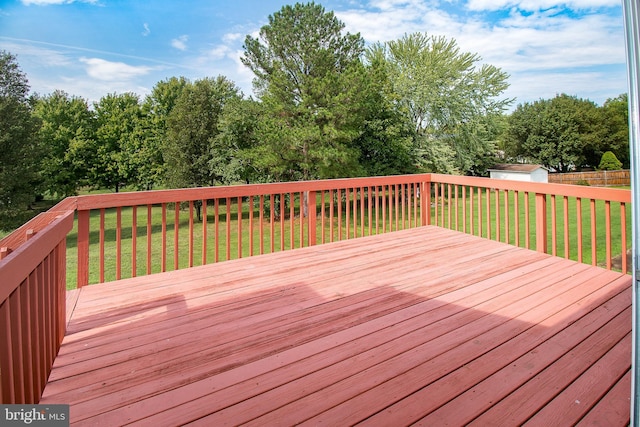 wooden terrace featuring a shed, an outdoor structure, and a yard