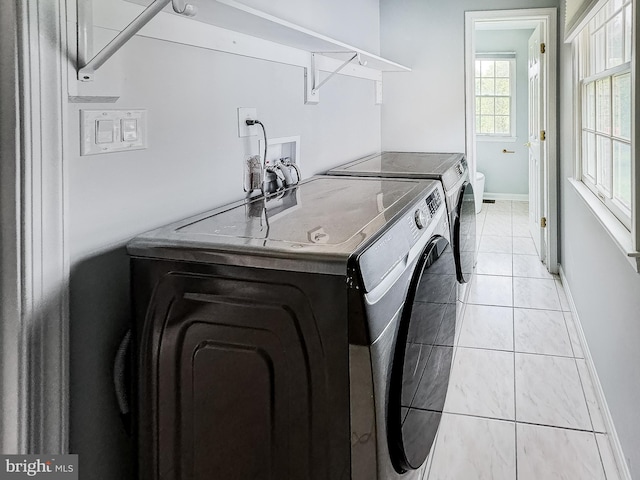 clothes washing area with baseboards, independent washer and dryer, light tile patterned flooring, and laundry area