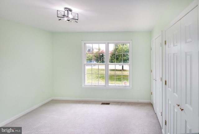 carpeted spare room with visible vents and baseboards